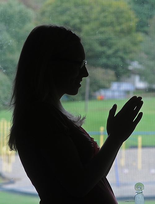 Silhouetted by the playground where her children play, a pregnant young mother, who is a survivor of domestic violence, says an afternoon prayer. (Dan Cappellazzo/Staff Photographer)